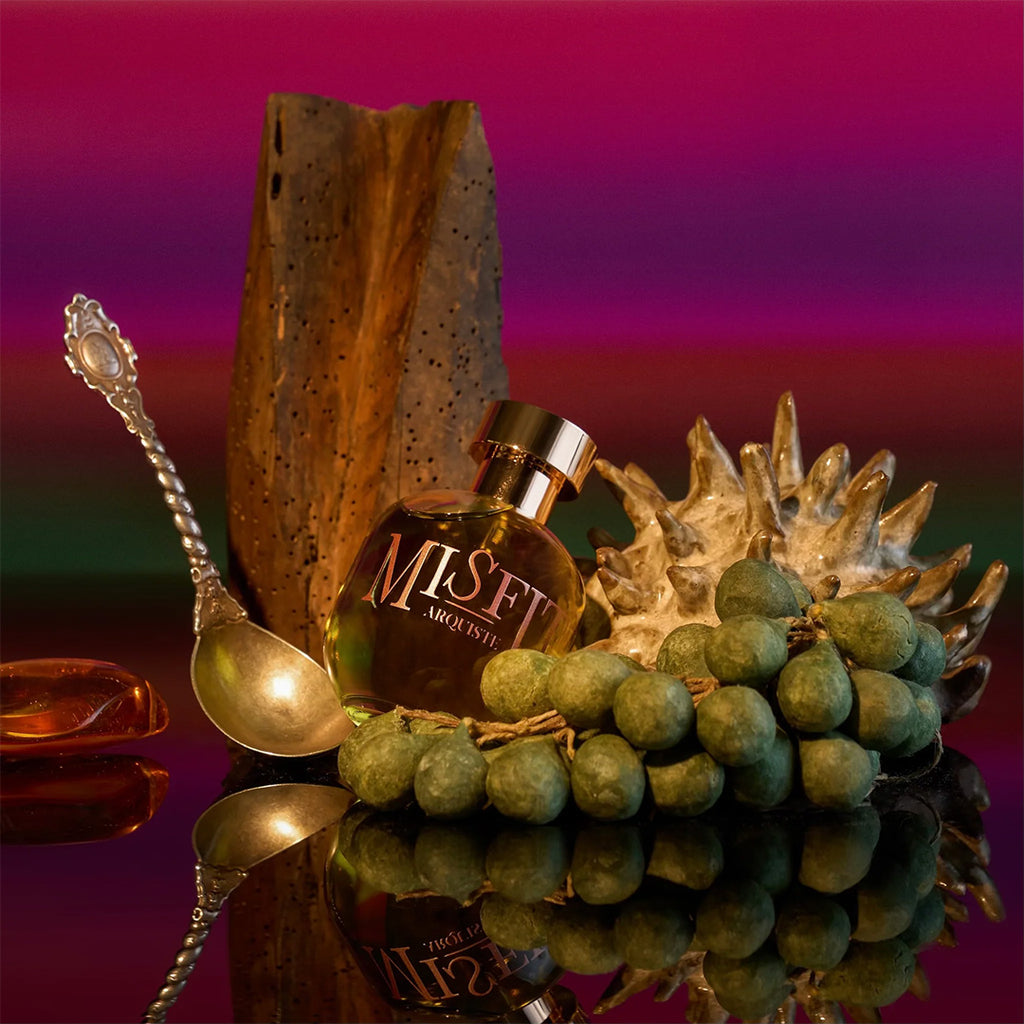 arquiste misfit perfume bottle silver spoon and grapes with gradient background
