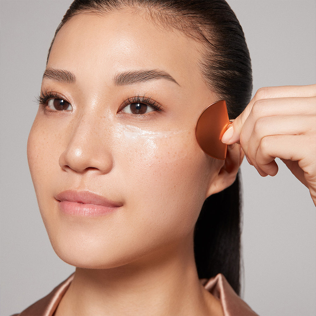 woman applying augustinus bader the face cream mask with applicator to her face