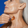 woman applying augustinus bader the face cream mask with applicator to her neck