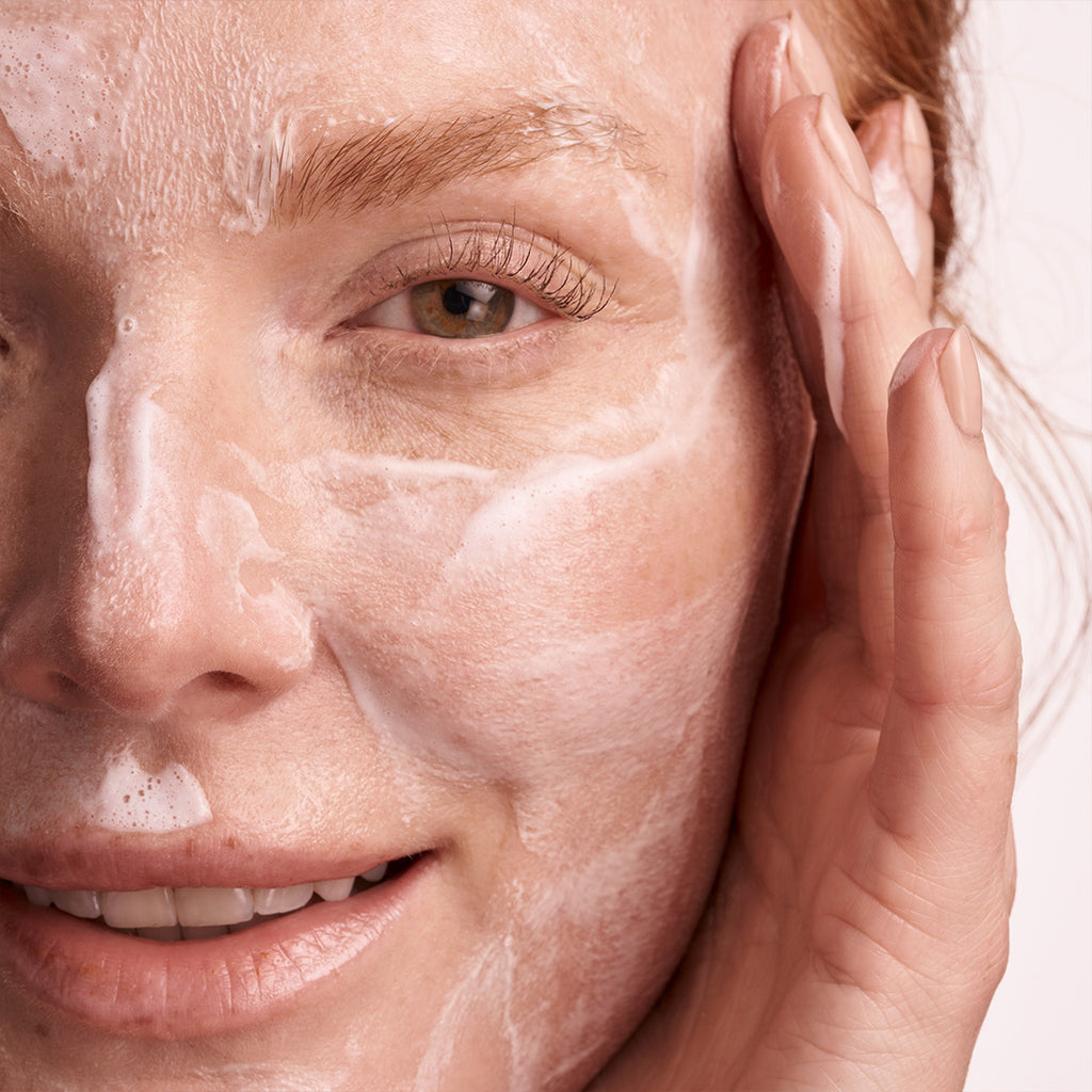 woman using augustinus bader the foaming cleanser on face