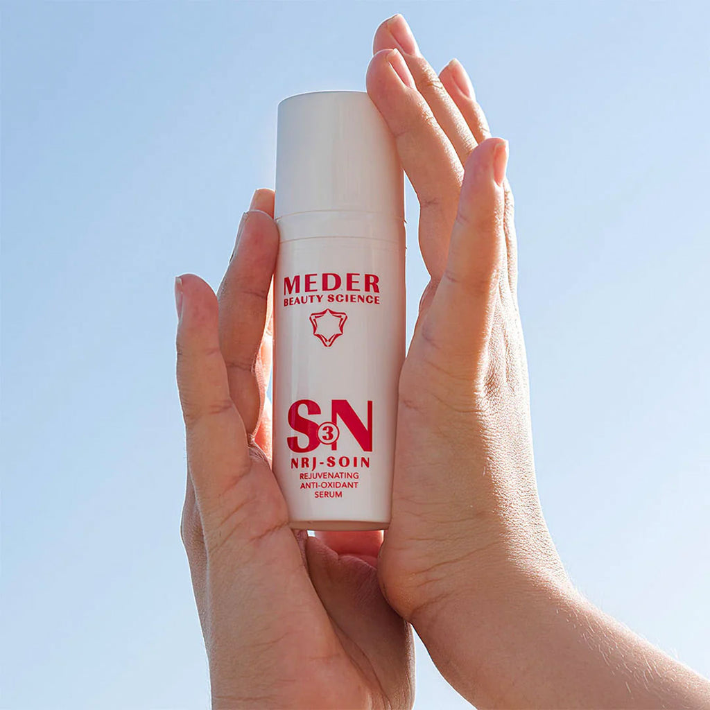 hand holding Meder Nrj-Soin Serum in the sky