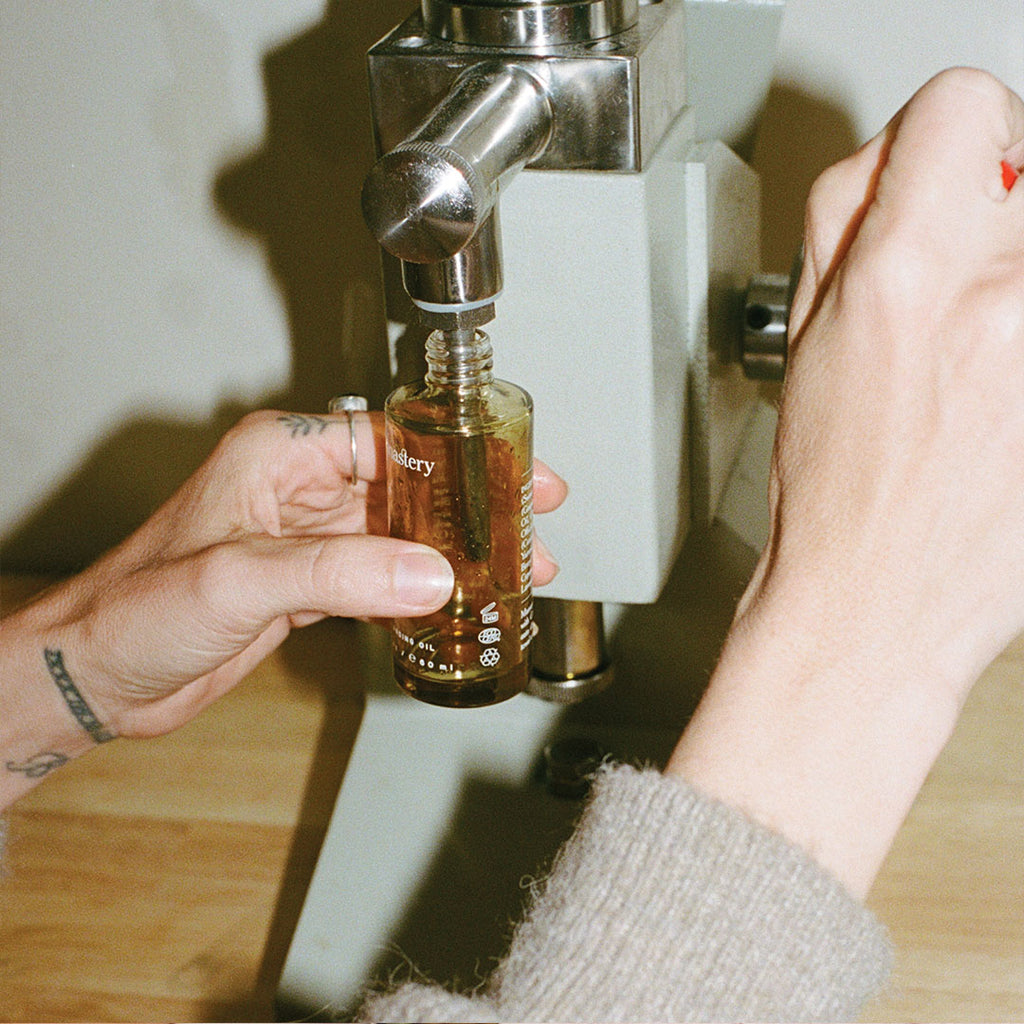 woman pouring Monastery Sage Cleansing Oil into bottle